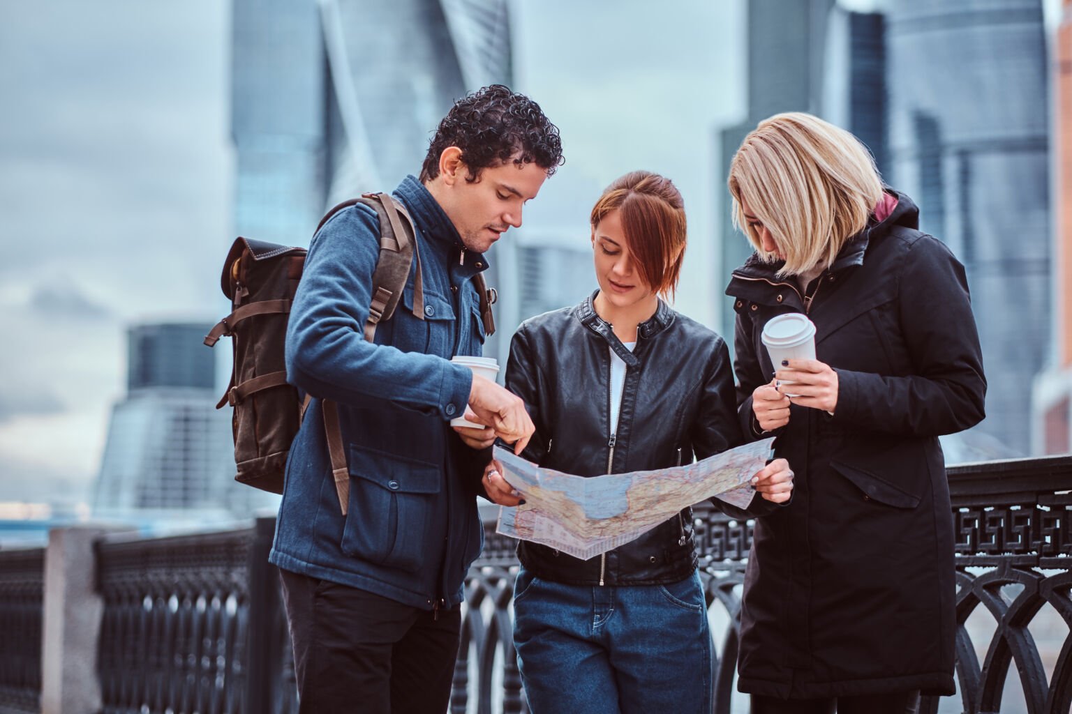group of tourists searching place on the map in front of skyscrapers